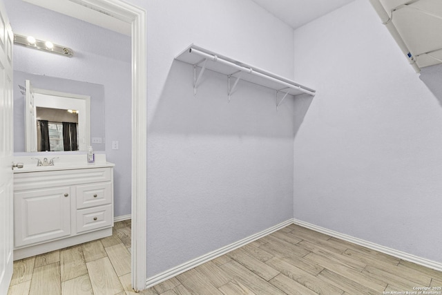 spacious closet with light wood-type flooring and a sink