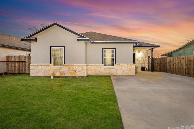 view of front of house with stone siding, fence, and a front lawn