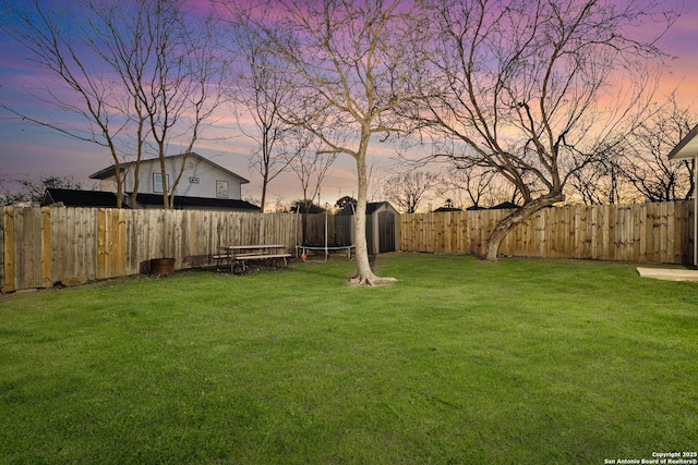 yard at dusk featuring a fenced backyard