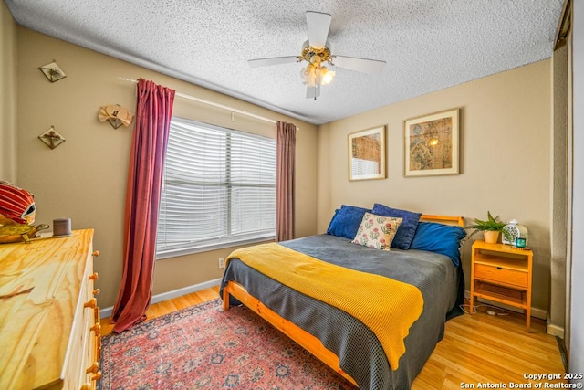 bedroom featuring a textured ceiling, wood finished floors, a ceiling fan, and baseboards