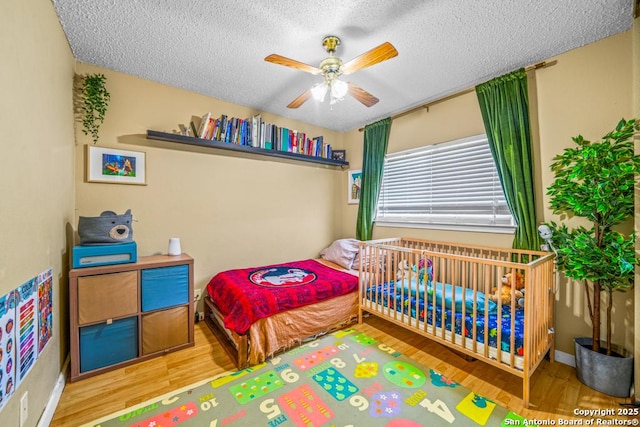 bedroom with ceiling fan, a textured ceiling, and wood finished floors