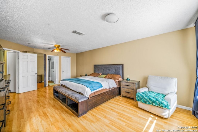 bedroom with visible vents, light wood-style flooring, a ceiling fan, a textured ceiling, and baseboards