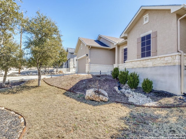 view of home's exterior with a garage, stone siding, and stucco siding