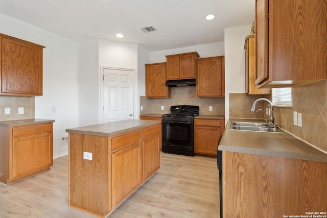 kitchen featuring black gas range, light wood-style floors, under cabinet range hood, and a sink