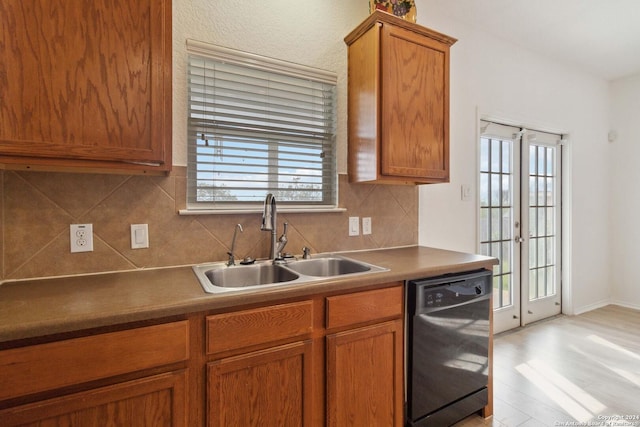 kitchen with dishwasher, light wood finished floors, a sink, and brown cabinets