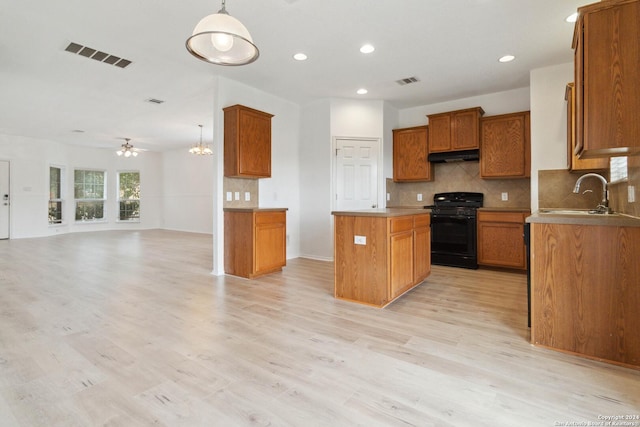 kitchen featuring black range with gas cooktop, visible vents, brown cabinets, open floor plan, and a sink