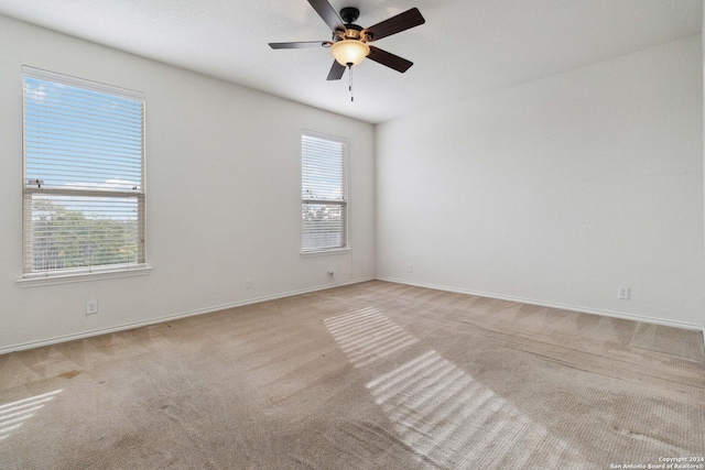 carpeted empty room with baseboards, a ceiling fan, and a healthy amount of sunlight