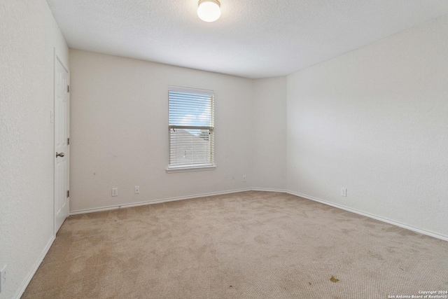 unfurnished room with a textured ceiling, carpet, and baseboards