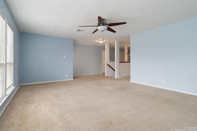 empty room with baseboards, visible vents, a ceiling fan, light colored carpet, and a textured ceiling