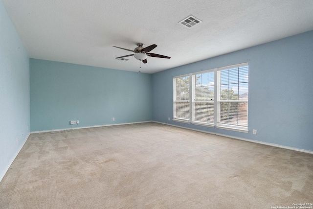 carpeted empty room with baseboards, a textured ceiling, visible vents, and a ceiling fan