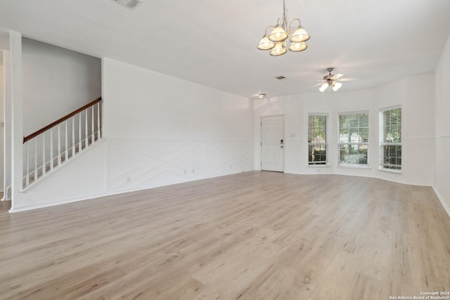 unfurnished living room with ceiling fan with notable chandelier, stairway, visible vents, and light wood-style floors