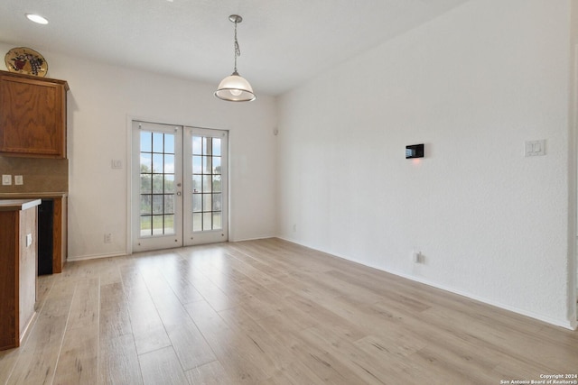 unfurnished living room featuring french doors, light wood-style flooring, and baseboards