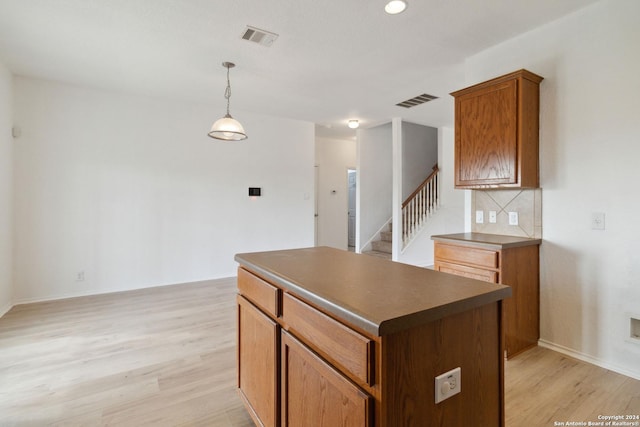 kitchen featuring dark countertops, light wood finished floors, visible vents, and a center island