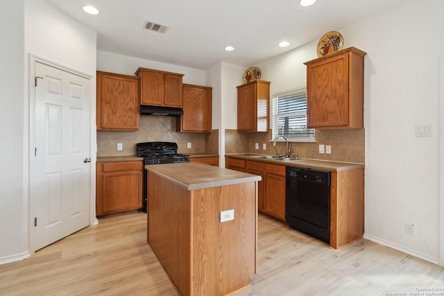 kitchen with under cabinet range hood, a sink, visible vents, brown cabinets, and black appliances