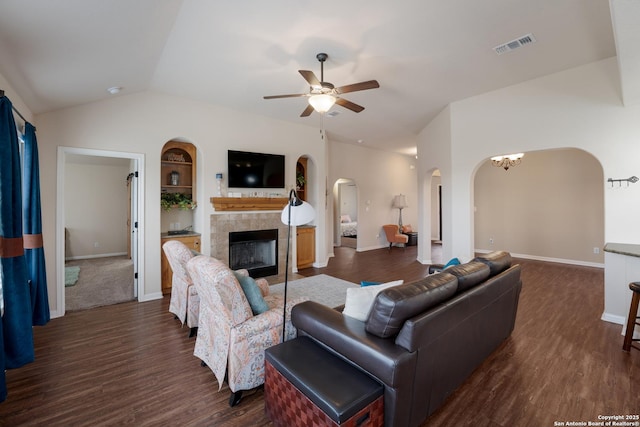 living area with visible vents, dark wood finished floors, a tiled fireplace, and ceiling fan with notable chandelier