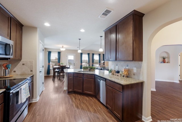 kitchen with stainless steel appliances, visible vents, a peninsula, and dark wood-style floors