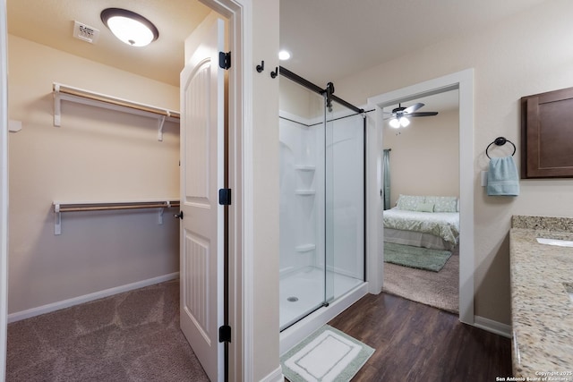 bathroom featuring visible vents, a spacious closet, a stall shower, vanity, and baseboards