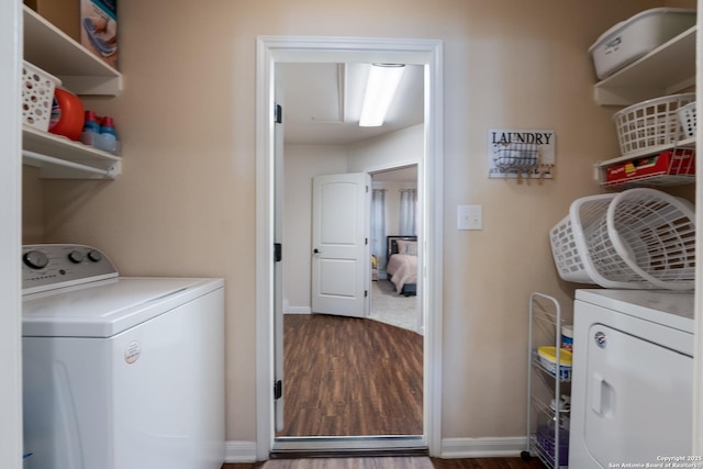 clothes washing area featuring wood finished floors, laundry area, baseboards, and separate washer and dryer