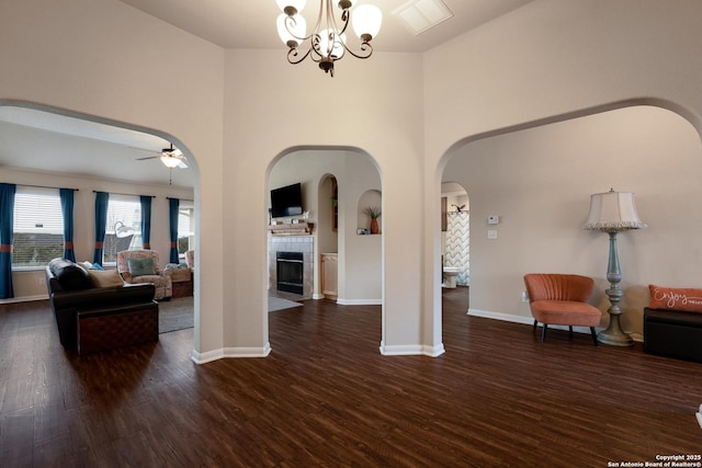 interior space featuring baseboards, arched walkways, dark wood-style flooring, and ceiling fan with notable chandelier