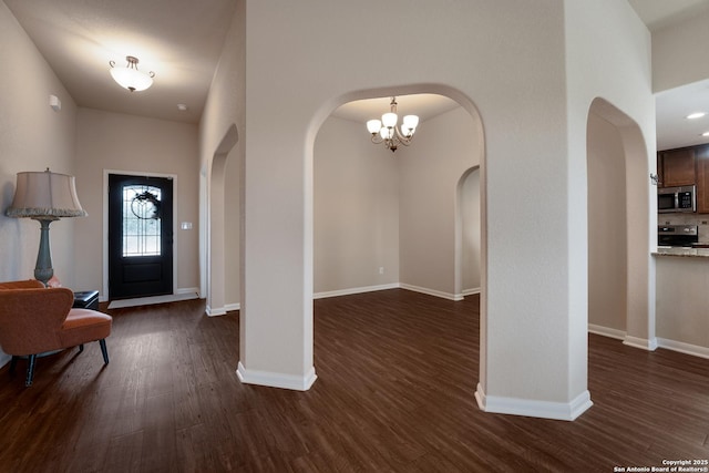 foyer entrance featuring arched walkways, dark wood finished floors, and baseboards