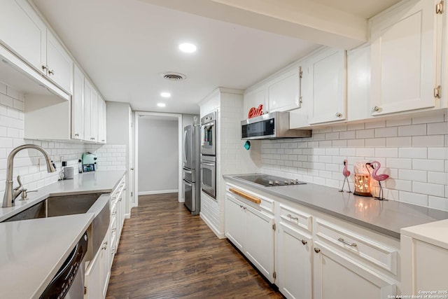 kitchen with appliances with stainless steel finishes, dark wood finished floors, visible vents, and white cabinets