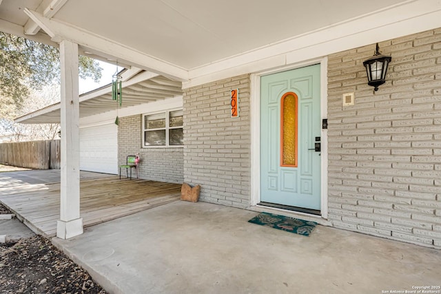 view of exterior entry featuring a garage and brick siding