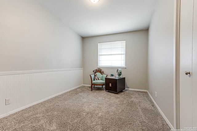 living area featuring a wainscoted wall and carpet