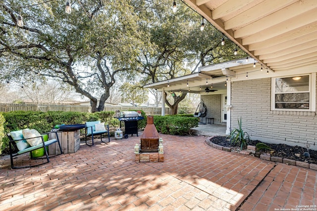 view of patio with a ceiling fan, fence, a fire pit, and area for grilling