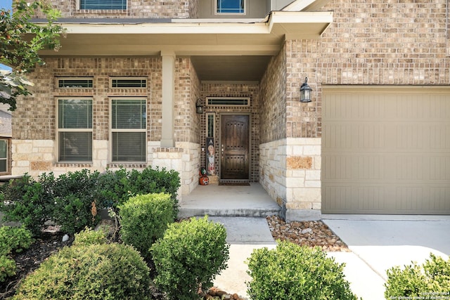 view of exterior entry with a garage and brick siding