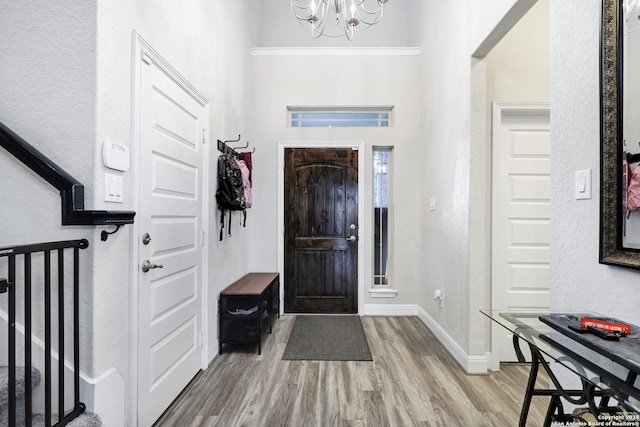 entrance foyer with baseboards, stairway, wood finished floors, and a notable chandelier