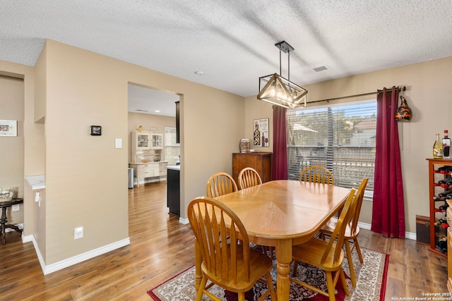 dining area with baseboards, visible vents, and wood finished floors