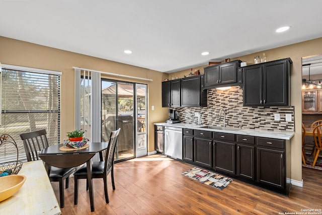 kitchen with a sink, light countertops, dishwasher, and wood finished floors