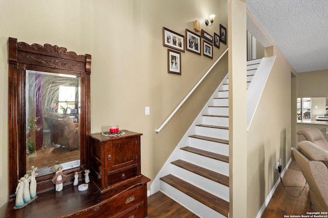 stairway featuring a textured ceiling, wood finished floors, and baseboards