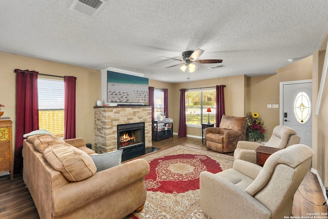 living area with visible vents, dark wood finished floors, and a stone fireplace