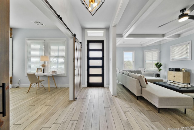 entryway with a barn door, visible vents, baseboards, light wood-type flooring, and beam ceiling