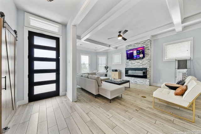 entryway featuring a fireplace, a barn door, ceiling fan, light wood-type flooring, and coffered ceiling