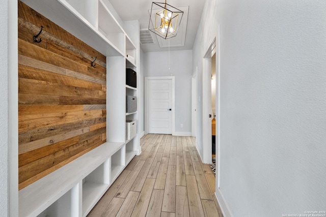 mudroom featuring light wood-style floors, attic access, and baseboards