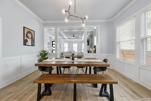 dining area featuring ornamental molding, light wood-style flooring, and a decorative wall