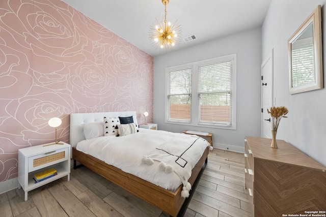 bedroom with wallpapered walls, baseboards, visible vents, and wood finished floors