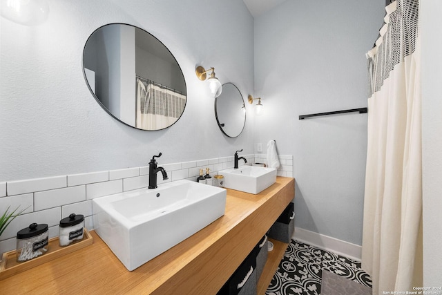 bathroom with double vanity, baseboards, decorative backsplash, and a sink