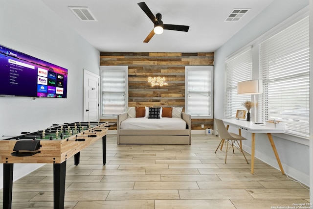 interior space with an accent wall, wood finish floors, visible vents, and wooden walls