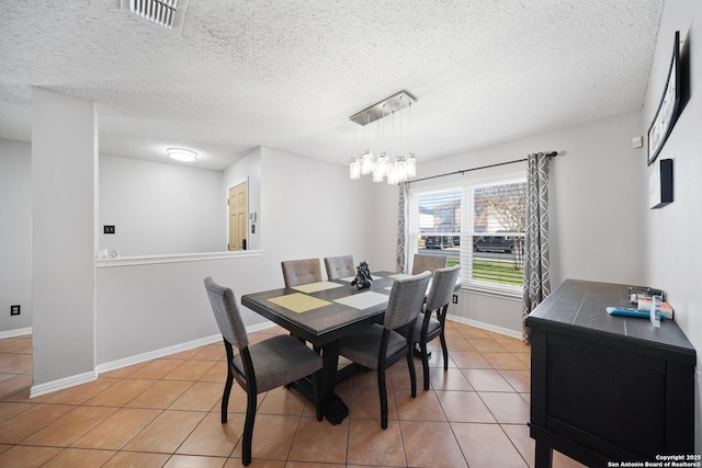 dining area featuring baseboards, visible vents, a textured ceiling, and tile patterned floors