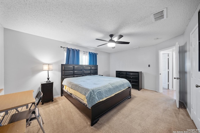 bedroom featuring a ceiling fan, visible vents, light carpet, and a textured ceiling