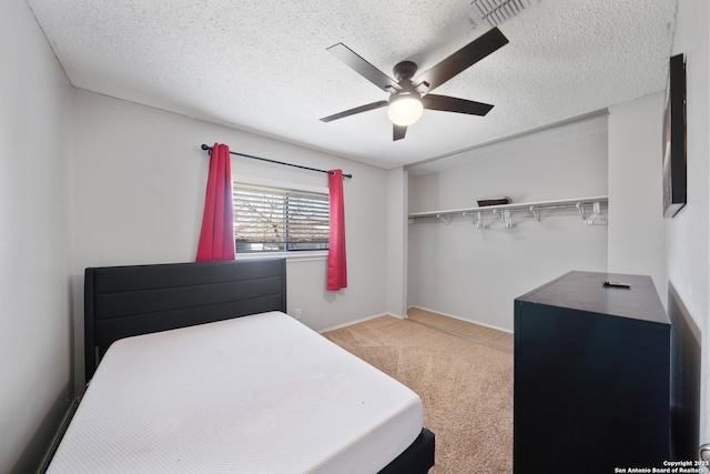 bedroom with light carpet, visible vents, a textured ceiling, and a ceiling fan