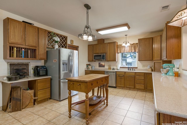 kitchen featuring visible vents, appliances with stainless steel finishes, brown cabinets, a sink, and light tile patterned flooring