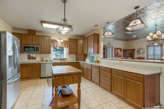 kitchen featuring wooden counters, appliances with stainless steel finishes, decorative light fixtures, and brown cabinets