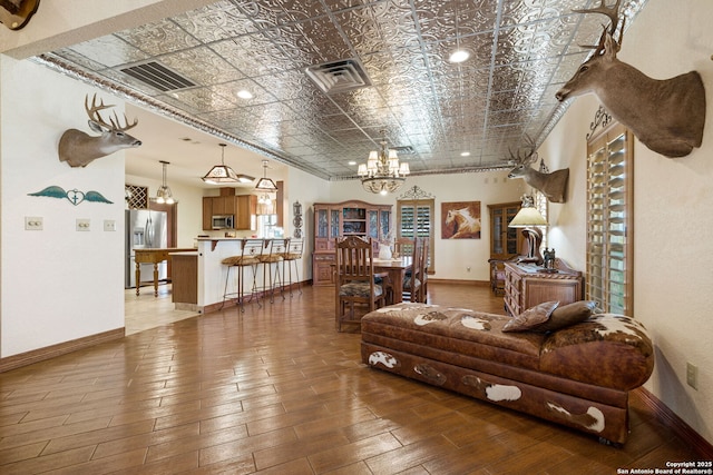 living area featuring an ornate ceiling, a chandelier, visible vents, and baseboards