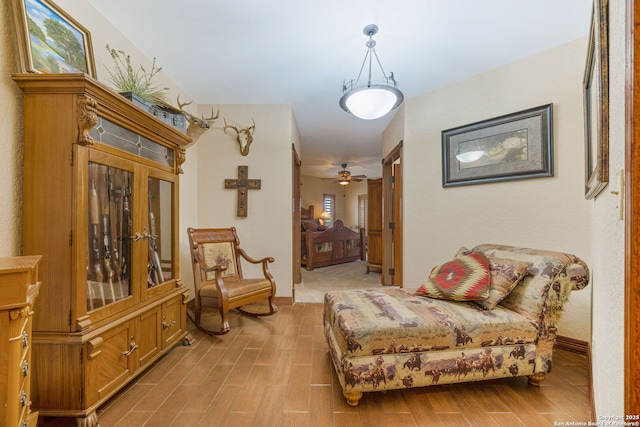 sitting room featuring wood finish floors, a ceiling fan, and baseboards