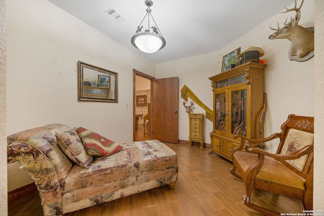 living room with wood finished floors, visible vents, and baseboards