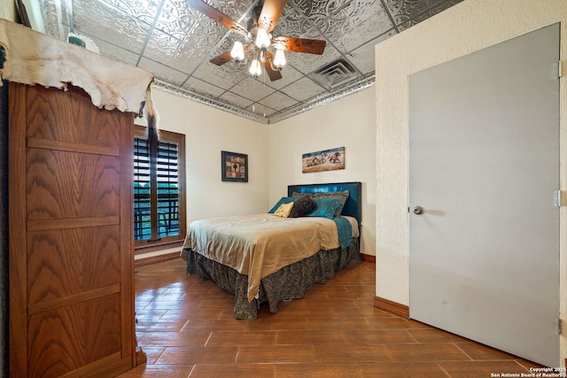 bedroom with baseboards, visible vents, a ceiling fan, an ornate ceiling, and wood tiled floor